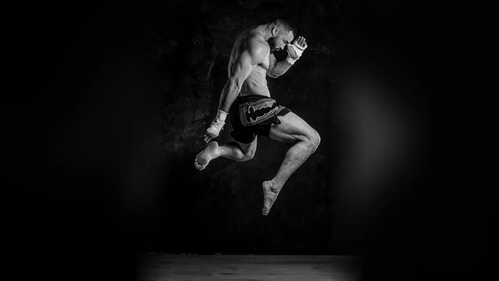 Peleador de muay thai saltando con la rodilla en alto